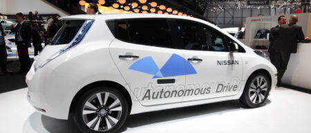 A white car, with automatic drive printed on it. Driverless car.